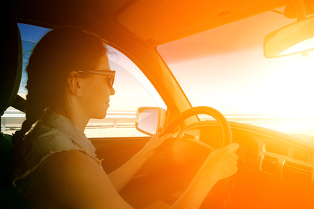 young woman driving to sunsetの写真素材