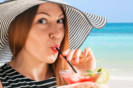 young woman in sunhat drinks cocktialの写真素材