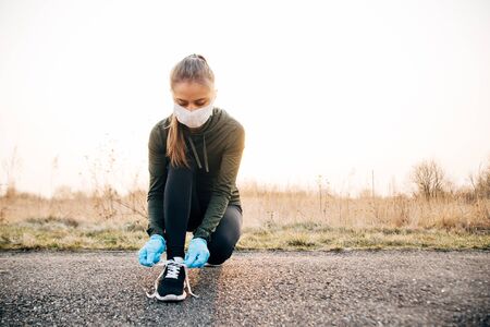 COVID-19 Pandemic Coronavirus girl in mask and blue gloves during quarantine went out to runの写真素材