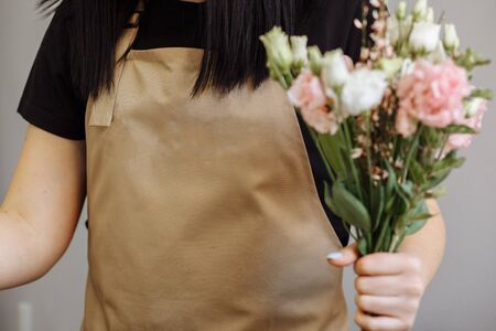 florist girl in sand apron at work creates a bouquet with eustomasの写真素材