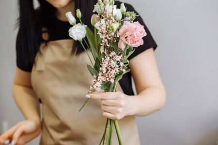 florist girl in sand apron at work creates a bouquet with eustomasの写真素材