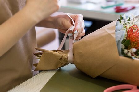 florist hands create a bouquet of flowers in a flower shopの写真素材
