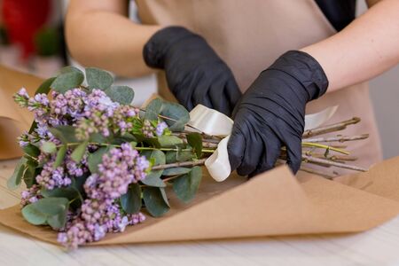 Lilac in the hands of a florist girl who creates a bouquet in a flower shopの写真素材
