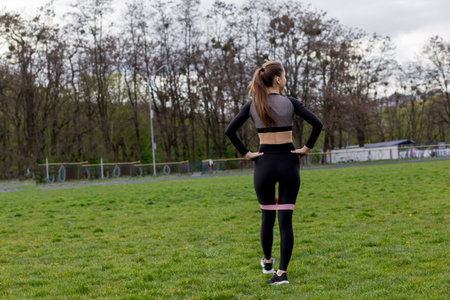 Fitness girl workout with fitness elastic bands in black tracksuit outdoors
