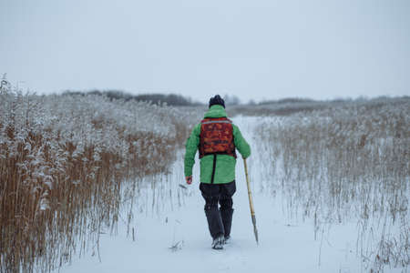 young male fisherman makes a hole in a snowy lakeの写真素材