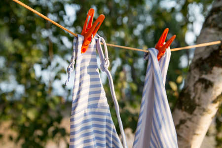 women's swimsuit pinned on a thread dries in the sunの写真素材