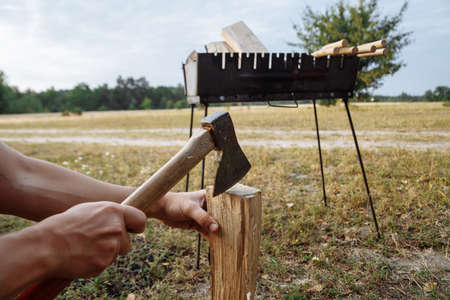a man in a camping town chops firewood with an ax for a barbecueの写真素材