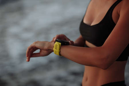 beautiful girl in a black swimsuit enjoys a smart sports watch by the seaの写真素材