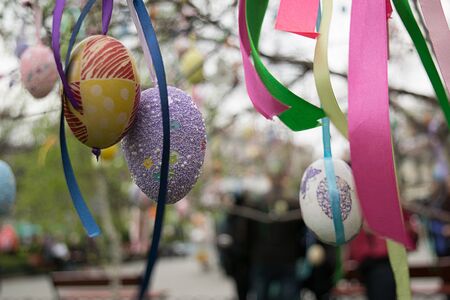Festively decorated Easter eggs hanging on a tree on a ribbonの写真素材