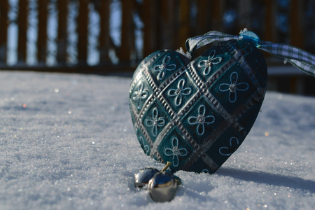 blue vintage heart with floral ornament close-up in the snow on a sunny dayの写真素材