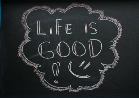 The inscription life is good and the smiley is white chalk on a dark griffeyev background in a frameの写真素材