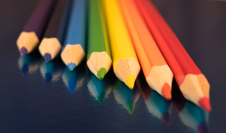 seven colors of the rainbow pencils on a dark blue glossy backgroundの写真素材
