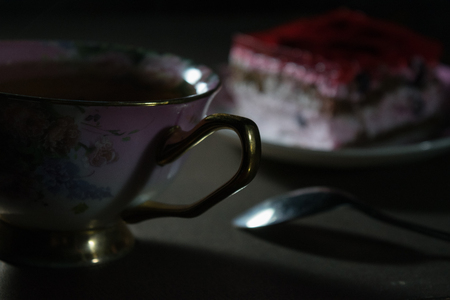 Beautiful biscuit cake with jelly and berries on a plate with a cup of teaの写真素材
