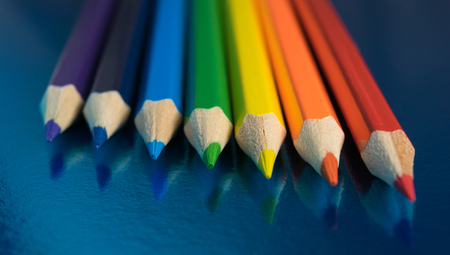 seven colors of the rainbow pencils on a dark blue glossy backgroundの写真素材