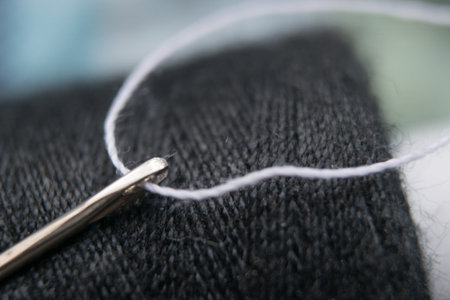 needle and white thread in a coil of black thread