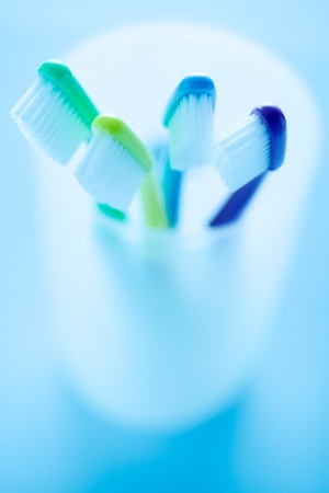 Close-up of four multicolored toothbrushes in white holder against blue backgroundの写真素材