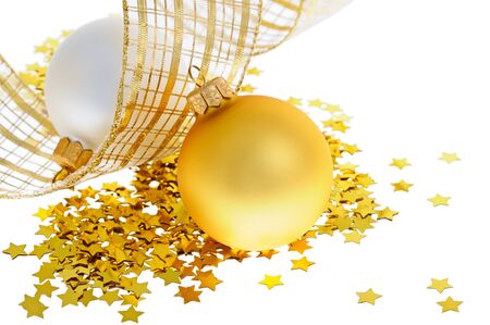 Two christmas balls on heap of confetti stars with yellow ribbonの写真素材