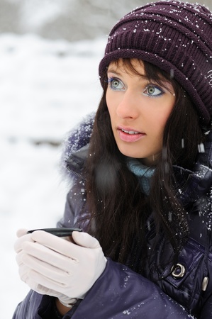 Portrait of the beautiful girl drinking hot beverage in snowy winter.の写真素材