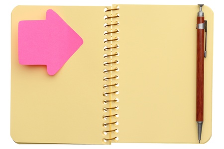 Open spiral notebook with post-it note in shape of arrow and pen isolated on white backgroundの写真素材