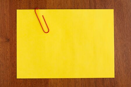 Blank yellow note with red clip on wooden background. Just add your textの写真素材