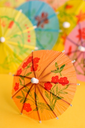 A paper drink umbrellas on orange backgroundの写真素材