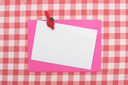 Blank message or invitation card with red envelope on red and white checked gingham tablecloth の写真素材