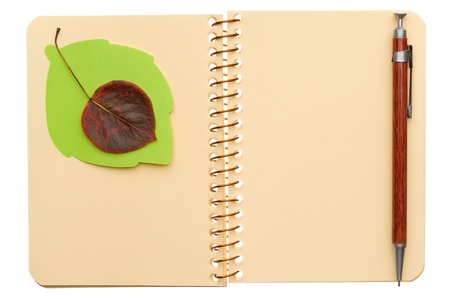 Opened spiral notebook with autumn leaf and pen isolated on white backgroundの写真素材