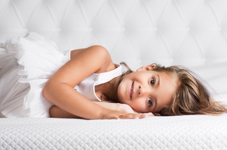 Portrait of cute girl lying in the bedの写真素材