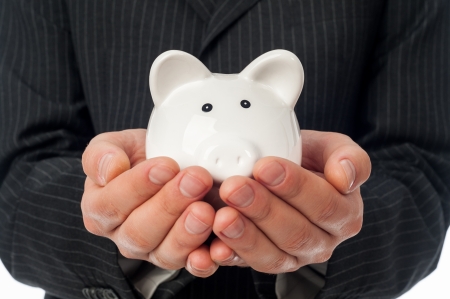 Man holding white piggy bank over black suit background の写真素材