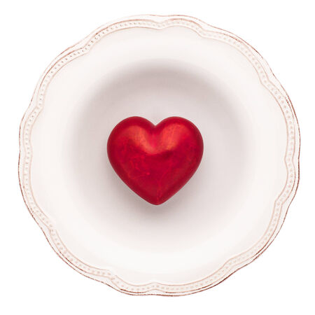 White dinner plate with red heart in it, view from above, isolated on white.の写真素材