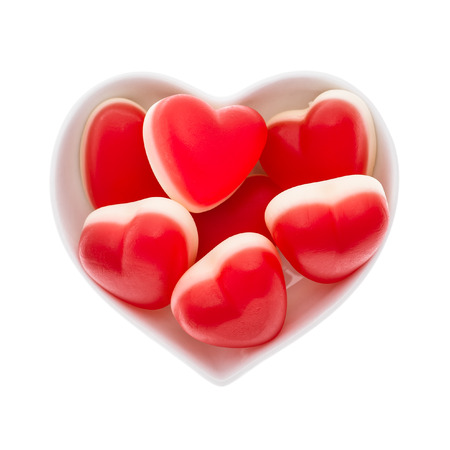 Red heart shaped sweets in the white heart shaped plate isolated over white.の写真素材