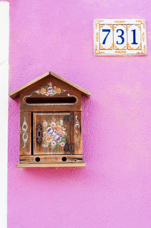The painted mailbox with house number on the side. Pink wall of house on Burano island, Venice, Veneto, Italy.の写真素材