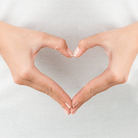 The form of heart shaped by female hands on body background isolated on white.の写真素材