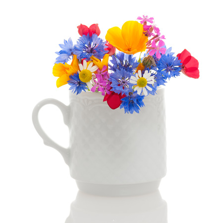 White textured cup with wildflowers isolated on white background の写真素材