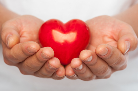 Man with red heart in his hands over body background.の写真素材