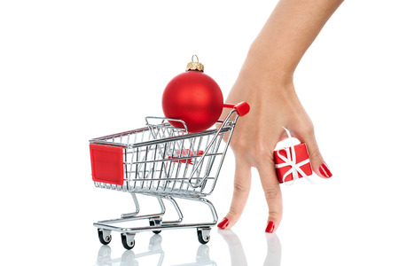 Woman hand imitating a customer with shopping trolley isolated on white background. Conceptual image - buying christmas presents.の写真素材