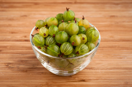 Gooseberries in a glass bowl on wooden table, close-up. の写真素材
