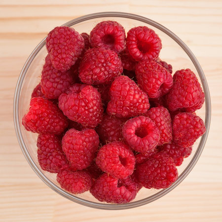Raspberries in a glass bowl on wooden table, close-up. の写真素材