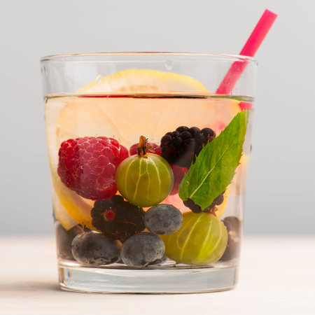 Summer lemonade with gooseberry, blackberries, blueberries, raspberries, lemon and mint. Glass with straw.の写真素材