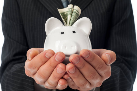 Man holding white piggy bank with dollar inside over black suit background.の写真素材