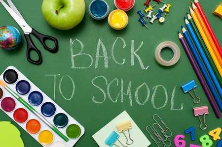 School supplies on blackboard background. "Back to school" written on green blackboard. Education concept の写真素材