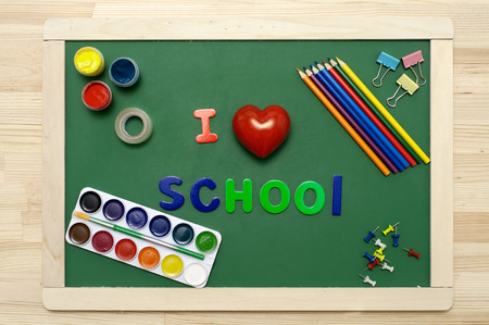 'I love school' phrase made with multicolored letters on green chalkboard with stationery.の写真素材