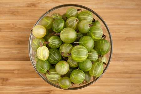 Gooseberries in a glass bowl on wooden table, close-up. の写真素材