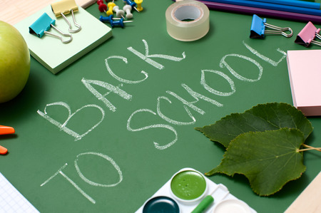 School supplies on blackboard background. "Back to school" written on green blackboard. Education concept. Angle view.の写真素材