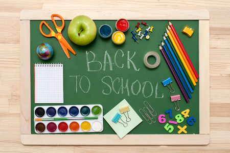 School supplies on blackboard background. "Back to school" written on green blackboard. Education concept の写真素材