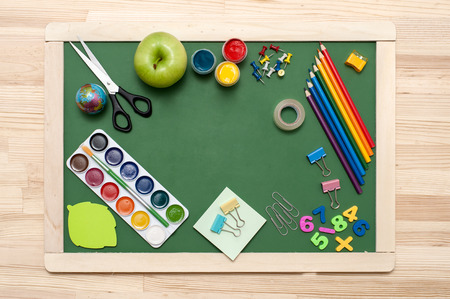 School supplies on blackboard background. Empty space in the middle of green blackboard. Education concept の写真素材