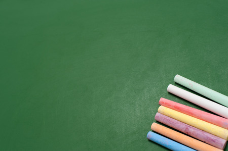 Closeup of blank green blackboard with pieces of coloured chalks.の写真素材
