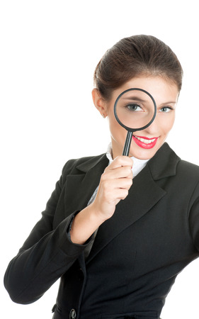 Woman in business dress looking through a magnifying glass. She is searching for something.の写真素材