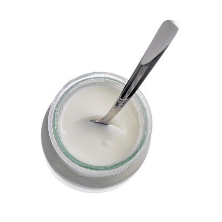 Glass yogurt pot with a spoon isolated on a white background.の写真素材