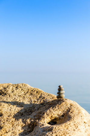 Stack of pebbles on a big rock at the beach on the blue background, with copy space.の写真素材
